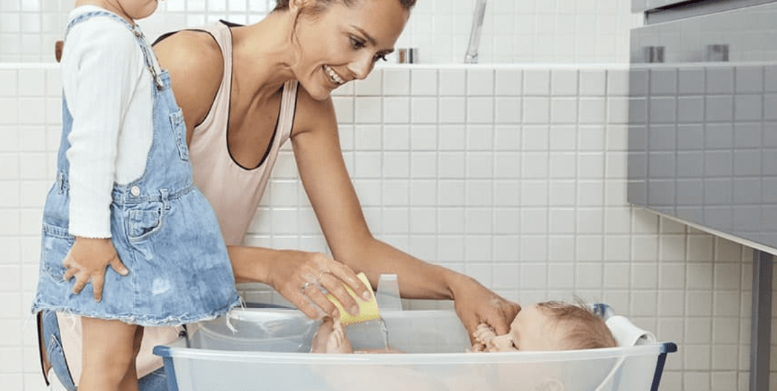 Baby liegt im Stokke Flexi Bath und die Mama badet es