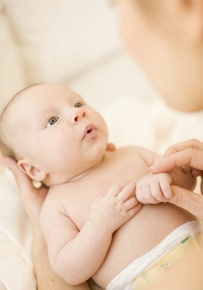 Ein Baby liegt in den Händen seiner Mutter und schaut verzückt.