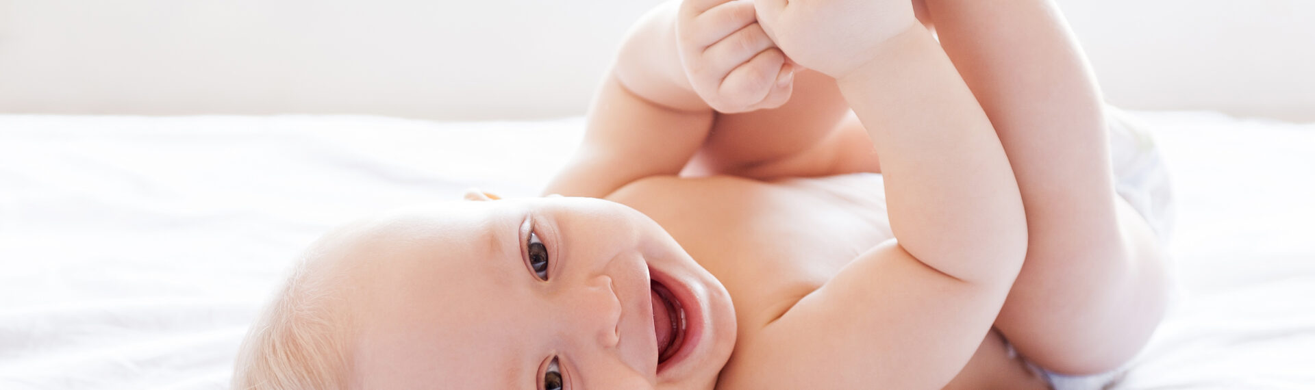 Baby liegt lachend auf dem Rücken