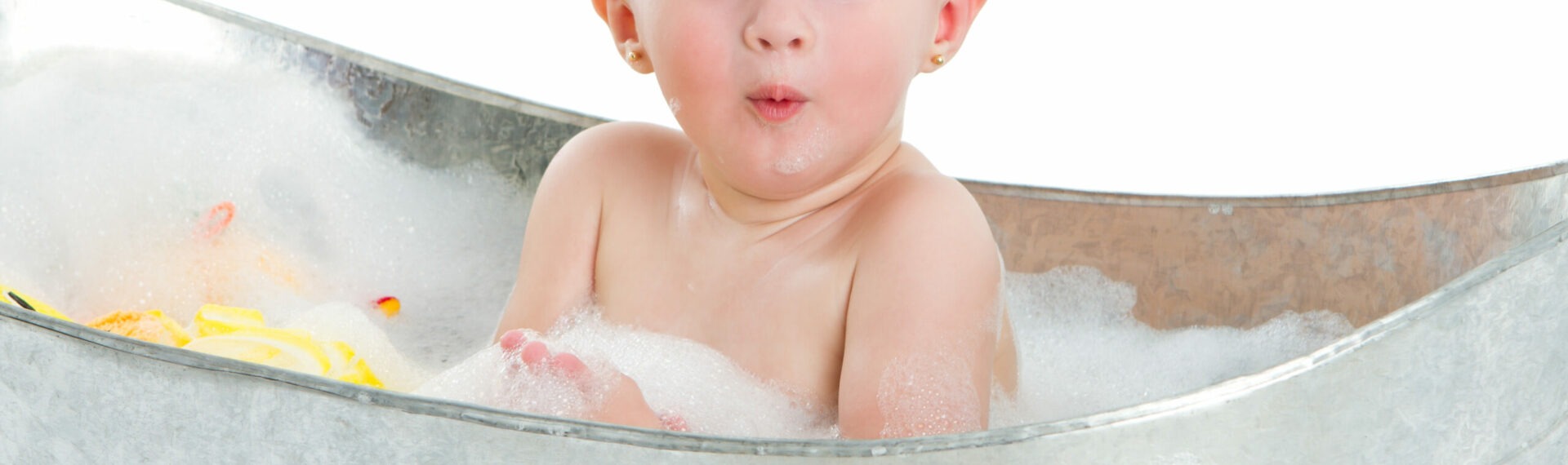Süßes 1 jähriges kleines Mädchen guckt überrascht und hat Spaß in der Badewanne