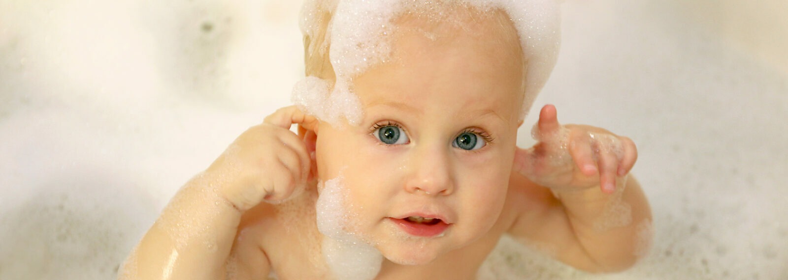 Baby ist in der Badewanne und komplett mit Badeschaum bedeckt