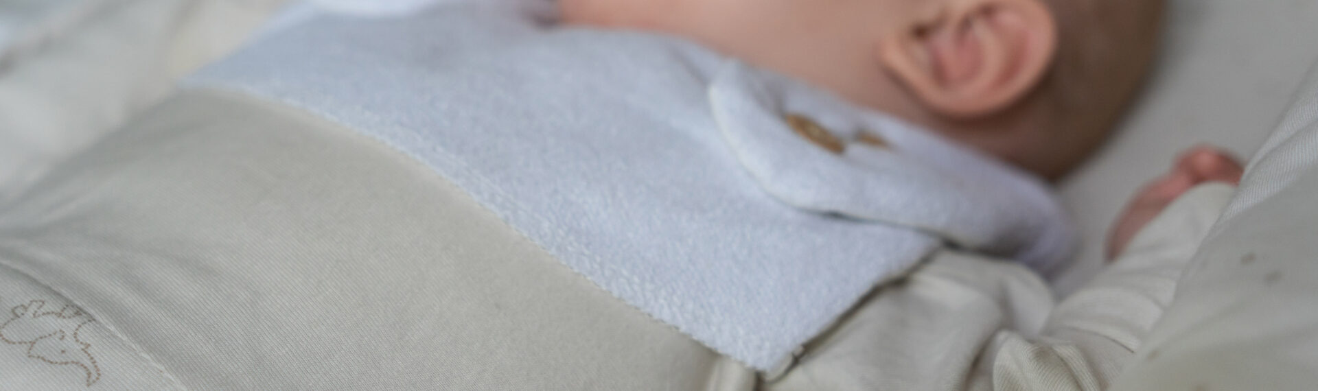 Baby liegt mit einem Schlafsack im Bett und schläft