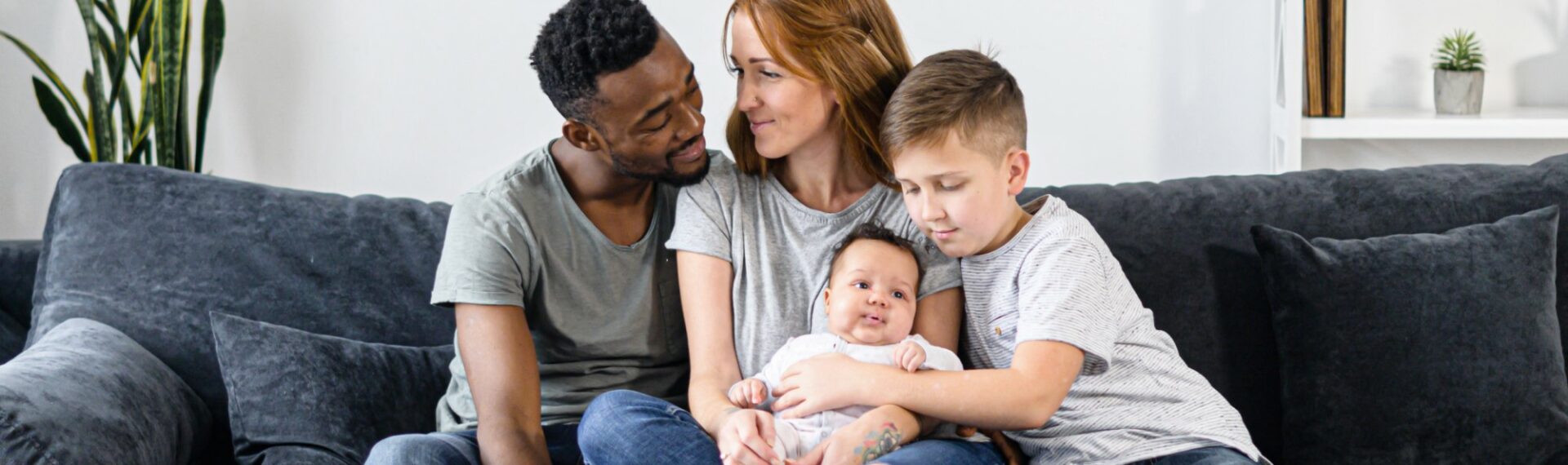 Familie mit Baby und Sohn im Grundschulalter auf einem Sofa