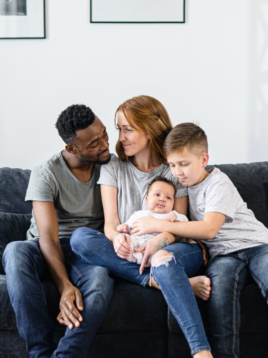 Familie mit Baby und Sohn im Grundschulalter auf einem Sofa